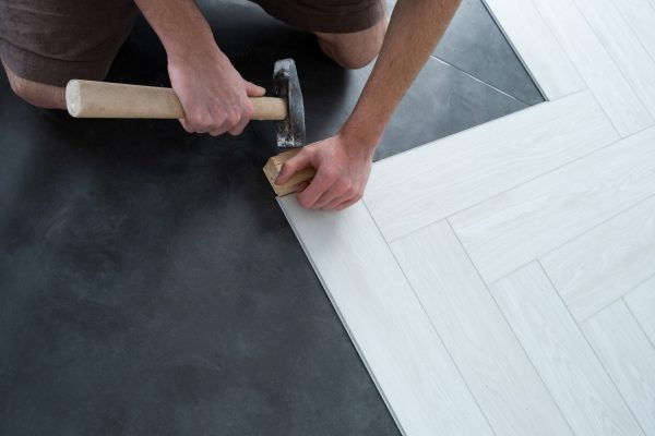 A man lays a quartz laminate on the floor. Renovation of premises. Installation of Modern flooring